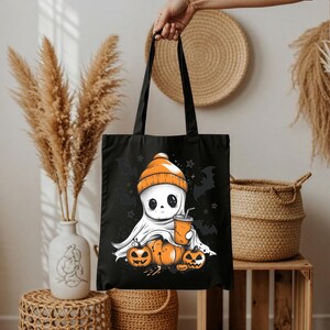 Op de afbeelding: Zwarte draagtas met een cartoongeest met een oranje muts en een drankje. De geest zit voor drie oranje pompoenen. Vleermuizen en sterren zijn op de tas gedrukt.