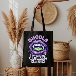 Könnte beinhalten: Schwarze Tragetasche mit einer lila-weißen Illustration von Vampirlippen und dem Text "GHOULS JUST WANNA HAVE FUN". Die Tasche hat zwei schwarze Griffe.