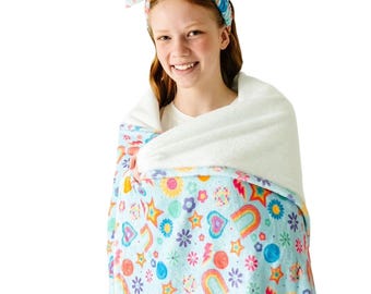 May include: A light blue blanket with a colorful pattern of rainbows, stars, flowers, and hearts. The blanket is wrapped around a person, and a matching headband is worn on the head.