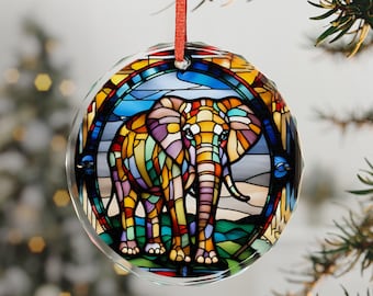 May include: A round, clear glass ornament with a stained-glass elephant design. The elephant is depicted in vibrant colors, including yellow, orange, purple, and blue. The ornament hangs from a red ribbon and is suitable for Christmas or other holiday decorations.