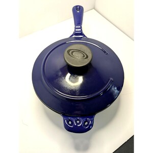 May include: A deep blue cast iron skillet with a matching lid. The skillet has a long handle and a small handle on the opposite side. The lid features a dark gray knob with a circular design. This cookware is ideal for stovetop and oven use.
