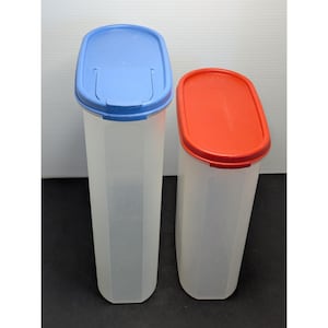 May include: Two clear, tall plastic containers with colored lids. One container has a blue lid, and the other has a red lid. The containers are designed with a faceted, geometric shape. The lids appear to have a hinged opening for easy access.