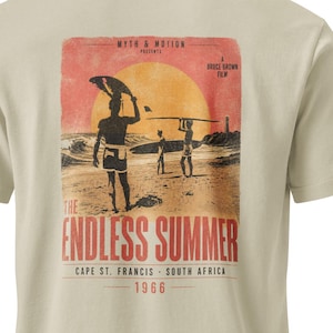 May include: Beige t-shirt featuring a vintage-style graphic from the film "The Endless Summer." The graphic depicts surfers on a beach at sunset, with text that reads "The Endless Summer" and "Cape St. Francis - South Africa 1966."