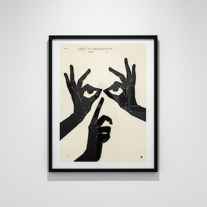 May include: Framed art print featuring a black and white graphic design. The artwork depicts silhouetted hands forming eyes and a finger to the lips, with the text "LOST IN CREATIVITY" at the top. The print is in a black frame.