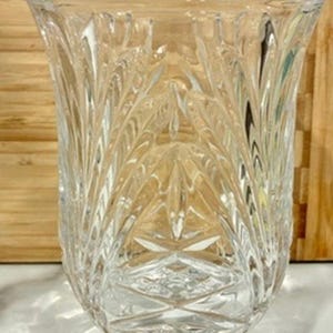 May include: A white ceramic mug with a black handle and the text "But First, Coffee" in a bold, black font. The mug is set against a blurred background, suggesting a cosy setting.