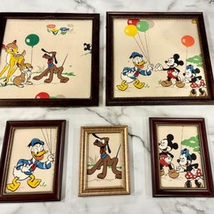 Puede incluir: Colección de arte enmarcado de personajes de Disney, con Bambi, Pluto, Donald Duck, Mickey Mouse y Minnie Mouse. La obra de arte incluye globos coloridos y detalles florales, sobre un fondo crema. Marcos marrones y dorados.