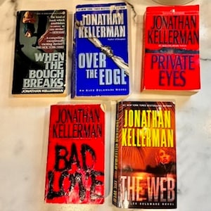May include: A collection of five paperback books by author Jonathan Kellerman, including the titles When the Bough Breaks, Over the Edge, Private Eyes, Bad Love, and The Web. Each book features distinct cover art with bold typography and colors.