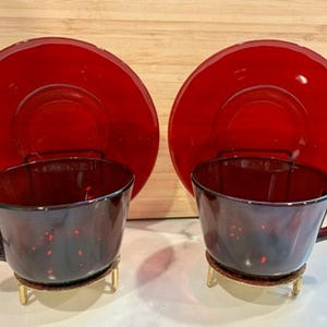 Puede incluir: Una taza de cerámica blanca con un asa negra y el texto "But First, Coffee" en negro, en negrita. La taza está sobre una superficie blanca.