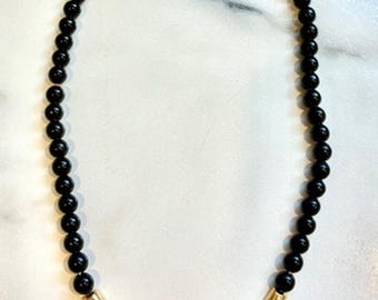 Collar de bisutería vintage de los años 80 con cuentas acrílicas negras y detalle central en forma de V y chevron dorado, 45 cm (18 pulgadas).