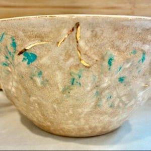 May include: A set of three ceramic mugs with a speckled, matte finish. The mugs are in shades of cream, light gray, and dark gray. Each mug has a simple, minimalist design, perfect for coffee or tea.