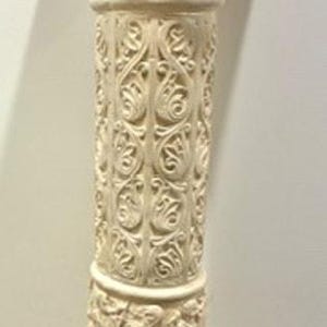 Puede incluir: Columna beige ornamentada con base cuadrada. La columna presenta tallas detalladas, incluyendo diseños florales y figurativos. La parte superior tiene una superficie plana y rectangular. Ideal para la decoración del hogar.