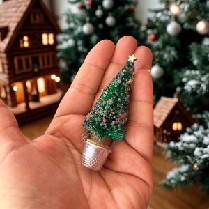 May include: A miniature Christmas tree, decorated with colourful beads and a gold star, held in a silver thimble pot. The tree is a festive decoration. The image shows a miniature Christmas scene.