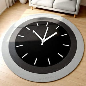 May include: A round rug with a clock face design. The rug features a black center with white clock hands and markers, surrounded by gray and light gray concentric circles. The rug is on a wooden floor.