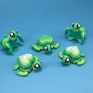 May include: Five handmade green and white turtle figurines with large, expressive eyes. The turtles are in various poses, set against a light blue backdrop. The turtle shells feature a unique, textured design.