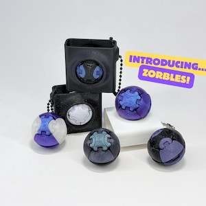 May include: A collection of spherical, puzzle-like toys in shades of purple, blue, and gray, with matching square cases. The text "INTRODUCING... ZORBLES!" is displayed on a yellow banner. The toys have a geometric design.