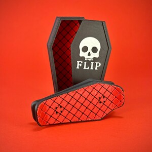 May include: A black coffin-shaped box with a red diamond pattern interior and a white skull graphic with the word "FLIP" on the front. A small black and red skateboard is in front of the box, on a red background.