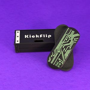 May include: Black skateboard deck with a green circuit board design and the word "Kickflip" on a black box. The skateboard decks are on a purple background.