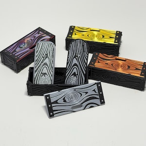 May include: A collection of miniature wooden chests and lids in various colors, including purple, gold, and orange. The chests have a black, textured wood grain appearance with metal accents. The lids feature a unique wood grain pattern.