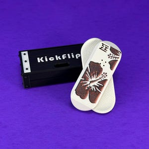 May include: White and brown flip-flops with a hibiscus flower design and a black box with the text "Kickflip" on a purple background. The flip-flops have a textured sole and a brown flower design.