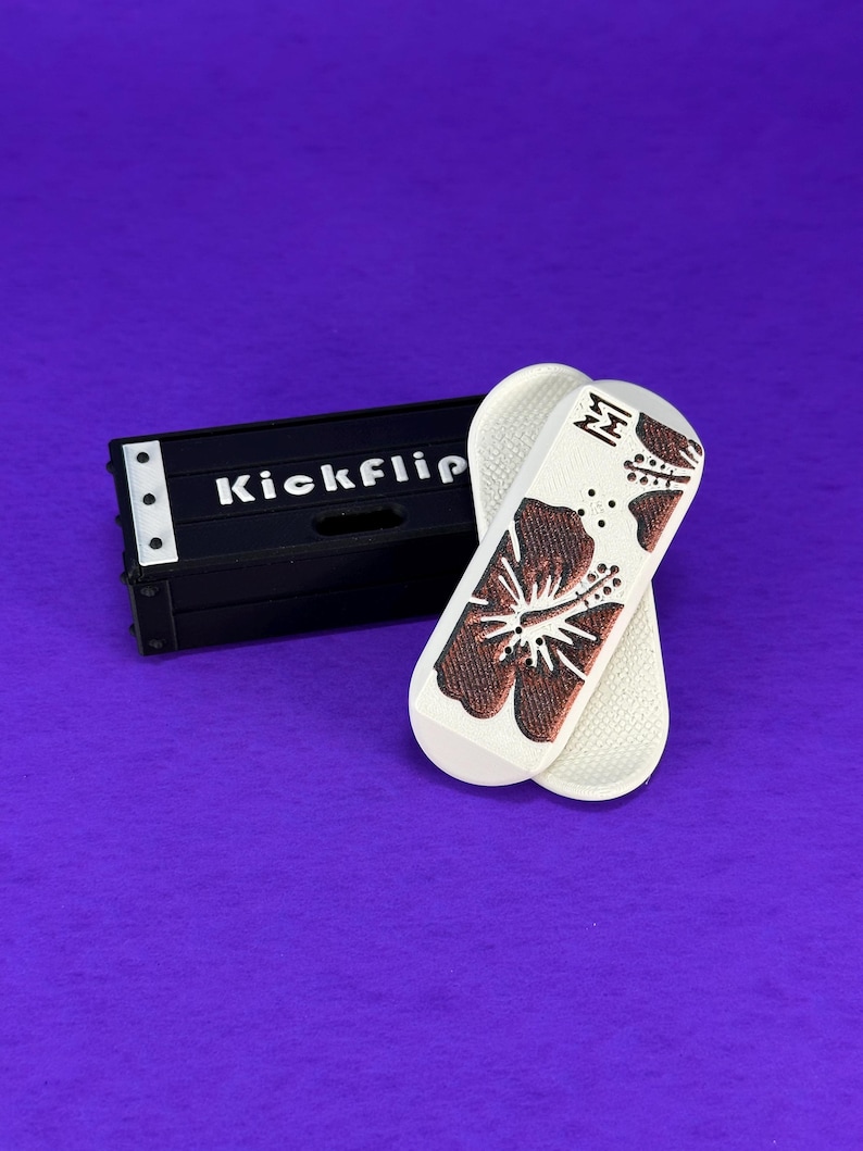 May include: White and brown flip-flops with a hibiscus flower design and a black box with the text "Kickflip" on a purple background. The flip-flops have a textured sole and a brown flower design.