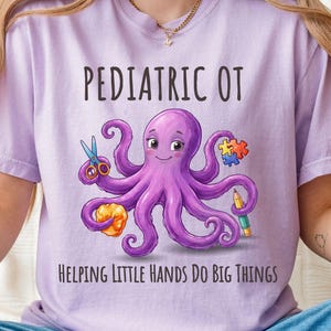 May include: A light purple t-shirt featuring a graphic of a purple octopus holding scissors, a puzzle piece, a yellow object, and a pencil. The text PEDIATRIC OT is printed above the octopus, and HELPING LITTLE HANDS DO BIG THINGS is printed below.
