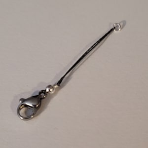 May include: A black cord necklace with a silver clasp and a small silver bead.
