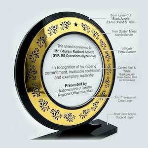 May include: A black and gold acrylic award with a circular design. The award features a golden mirror acrylic border with an intricate floral pattern. Text on the award reads, "This Shield is presented to Mr. Ghulam Rabbani Soomro..." and is presented by National Bank of Pakistan.