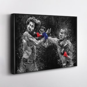 May include: Black and white framed print of a mixed martial arts fight scene. Two fighters are shown mid-action, with one throwing a punch. The fighters wear gloves with red and blue accents. The UFC logo is visible on the fighters' shorts.