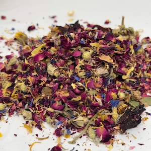 Op de afbeelding: Een hoop gedroogde bloemblaadjes en -knoppen in tinten rood, roze, geel en blauw. De mix bevat rozenblaadjes, korenbloemen en andere bloemelementen, waardoor een kleurrijke en gestructureerde weergave ontstaat. De afbeelding is een close-up.