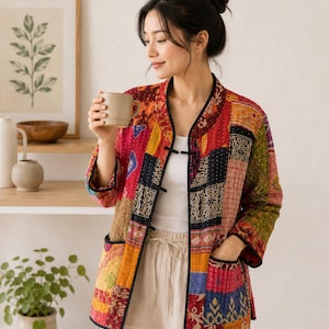 May include: A quilted jacket featuring a vibrant patchwork design with various patterns in shades of red, orange, yellow, blue, and green. The jacket has a mandarin collar, black trim along the edges, long sleeves, and two front pockets.