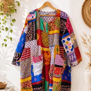 Puede incluir: Una túnica de manga larga con un diseño de patchwork vibrante que presenta varios patrones coloridos, incluyendo estampados florales, geométricos y de cachemira. La prenda tiene un cuello redondo, cierre frontal de botones y dos bolsillos delanteros, todo cosido con hilo blanco visible.