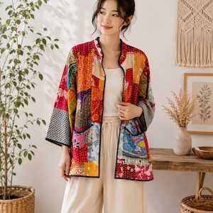 Könnte beinhalten: Eine langärmelige Jacke mit einem lebendigen Patchwork-Design aus verschiedenen Blumen- und geometrischen Mustern in Rot-, Gelb-, Blau- und Schwarztönen. Die Jacke hat einen Stehkragen, schwarze Kanten und zwei aufgesetzte Vordertaschen.