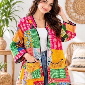 Può includere: Una giacca a maniche lunghe caratterizzata da un vivace design patchwork con vari motivi floreali e geometrici nelle tonalità del rosa, giallo, verde e blu. Il capo presenta un'apertura frontale, un bordo nero e due ampie tasche applicate.