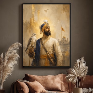 May include: A framed wall art print depicting a bearded figure wearing a blue and white turban and traditional attire, holding a falcon on one hand. The background features a golden-toned landscape with a building and a flag under a symbol.
