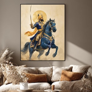 May include: A framed wall art print depicting a warrior in a blue and gold outfit riding a dark blue horse. The warrior holds a curved sword aloft, with a golden halo behind their head. The background is a textured, light beige parchment colour.