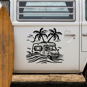 May include: A white vintage camper van with a wooden surfboard leaning against it on a sandy beach. The van has a black graphic of palm trees and a camper. The ocean is visible in the background.