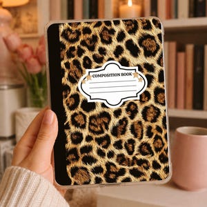 Op de afbeelding: Een compositieboek met een luipaardprint cover. De cover heeft een patroon van bruine en zwarte vlekken op een beige achtergrond. Het boek heeft een wit label met de woorden "COMPOSITION BOOK".