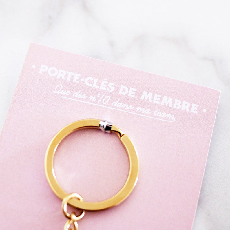 May include: A gold key chain with a pink card that says "PORTE-CL&Eacute;S DE MEMBRE. Que des n&deg;10 dans ma team."