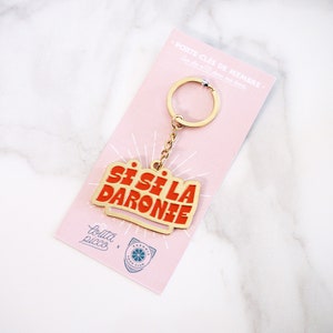 May include: Gold keychain with a red and gold metal charm that says "Si Si La Daronie". The keychain is on a pink card with the text "Porte-Cl&eacute;s de Membre" and "Lolita Picco x Daronie Food Club".