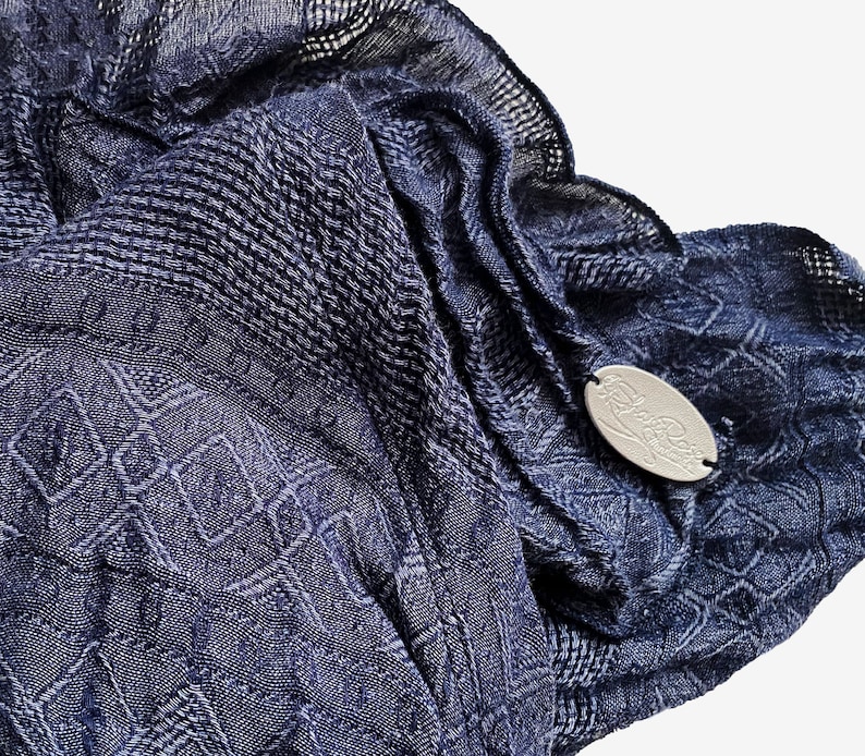 May include: A navy blue patterned scarf with a silver tag that says "Lola Rose".