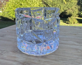 Peut inclure: Un récipient en verre transparent présentant une texture de surface à facettes, géométrique et angulaire. L'objet est de forme cylindrique avec une base épaisse et un motif répétitif de facettes triangulaires et quadrilatérales.