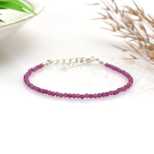 Op de afbeelding: Een delicate armband met kleine, gefacetteerde, dieproze edelstenen. De armband heeft een zilverkleurige ketting en sluiting. De edelstenen zijn gelijkmatig verdeeld, waardoor een doorlopende lijn van kleur ontstaat.