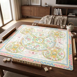 May include: A square mahjong mat featuring a central circular floral design surrounded by four smaller circular motifs, all decorated with pastel pink, green, and yellow patterns. The mat includes game instructions and text, with wooden tile racks.