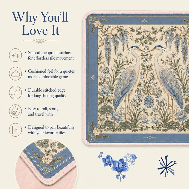 May include: A rectangular neoprene game mat featuring a cream background with a blue border and a central illustration of two herons surrounded by lotus flowers and wisteria. The mat has a light pink stitched edge and a smooth surface texture.