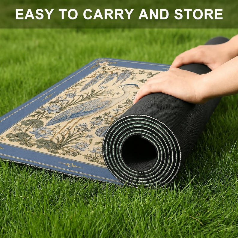 May include: A rectangular mat with a beige background featuring a blue heron and floral illustrations, bordered by a dark blue frame. The mat has a black textured underside and is partially rolled up. The text EASY TO CARRY AND STORE is visible.