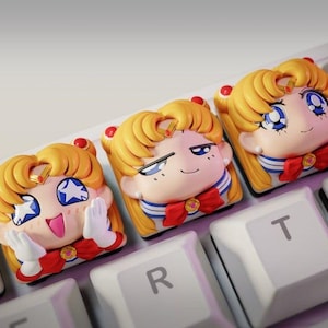 May include: Three custom keycaps featuring a cartoon character with blonde hair, blue eyes, and a red bow. The keycaps are on a white keyboard, with the characters on the keys. The keycaps are a unique accessory for mechanical keyboards.