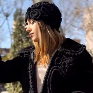Peut inclure: Chapeau noir au crochet avec un motif floral. L'image montre également une veste noire au crochet avec un motif assorti. L'image provient du compte Instagram @gayacrochet.