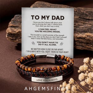 May include: A multi-strand bracelet featuring brown and gold tiger eye beads, a braided dark leather cord, and a smooth silver-tone metal plate engraved with the text LOVE YOU ALWAYS, paired with a card reading TO MY DAD.