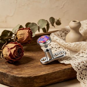 May include: A dermal anchor piercing with a vibrant, multi-colored opal stone. The jewelry is silver-toned and features a threaded post and a flat, oval base with two holes. The opal stone is set in a silver bezel.