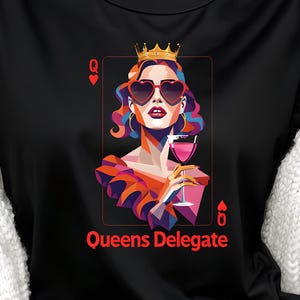 Puede incluir: Camiseta negra con un diseño gráfico colorido de una reina con gafas de sol en forma de corazón y una corona, sosteniendo una copa de vino. El texto "Queens Delegate" está impreso debajo. Cuello redondo.